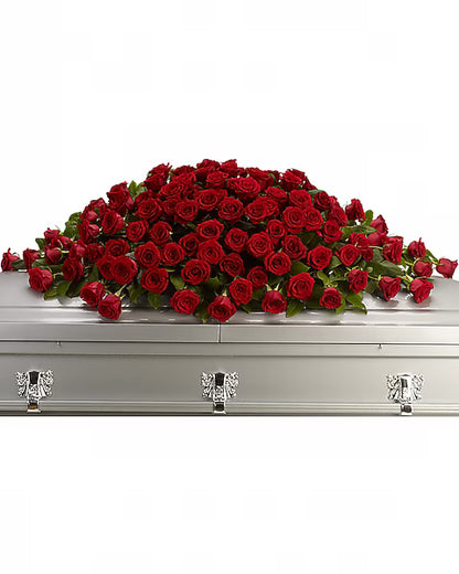 Silver casket with a large arrangement of red roses on a white background
